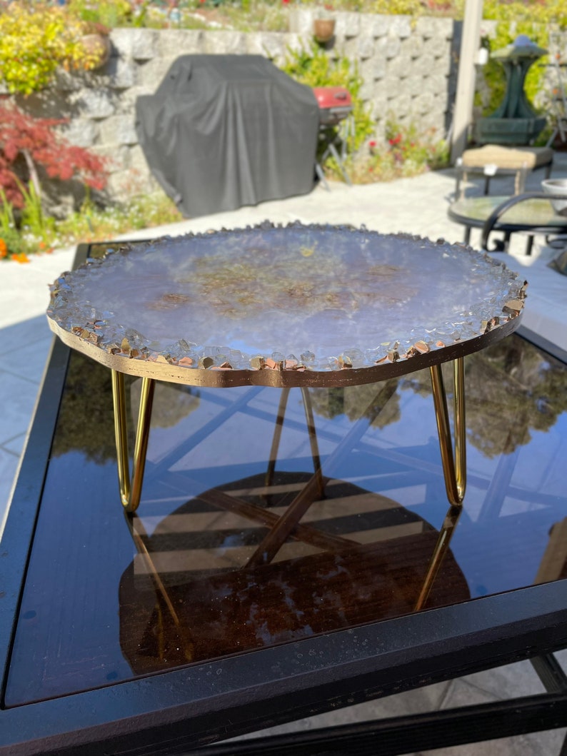 May include: A round, white agate slice table top with gold accents and a gold metal stand with three legs.