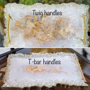 May include: Two white resin serving trays with gold accents. The top tray has twig handles and the bottom tray has T-bar handles. Both trays have a white background with gold flecks.