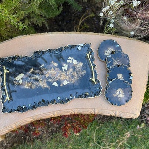 May include: A black resin serving tray with gold flecks and a gold handle. Four black coasters with gold flecks are also included.
