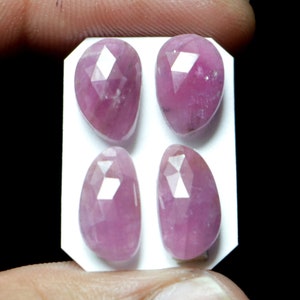 Peut inclure: Quatre pierres précieuses roses et magenta, taillées à facettes en forme de goutte d'eau, sont présentées sur un fond blanc. Les gemmes ont une surface polie et réfléchissante avec de multiples facettes. Ces pierres sont probablement destinées à la joaillerie ou à la collection.