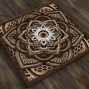Op de afbeelding: Een lasergesneden houten mandala-ontwerp met ingewikkelde details en een wit centrum. De mandala is ingelijst in een donkerhouten lijst en ligt op een houten oppervlak.