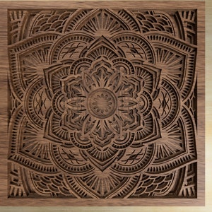 Op de afbeelding: Een gedetailleerd mandala-ontwerp dat in een stuk hout is gegraveerd. De mandala is ingewikkeld en symmetrisch, met een verscheidenheid aan vormen en patronen. Het hout is van een rijke bruine kleur, en de gravure is zeer precies.