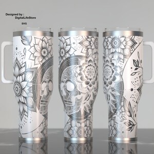 May include: Three white stainless steel tumblers with intricate black and gray floral and skull designs. Each tumbler has a handle and a silver rim. The text "Designed by: DigitalLifeStore SVG" is visible.