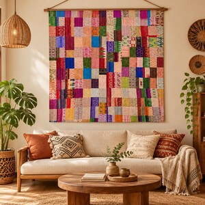 Könnte beinhalten: Ein großer rechteckiger Wandbehang, der aus zahlreichen kleinen, mehrfarbigen Stoffstücken besteht, die in einem Rastermuster zusammengenäht sind. Das Textil weist eine lebendige Palette an Farben auf, darunter Rot, Blau, Gelb, Grün und Pink, mit verschiedenen komplizierten Mustern und Texturen auf den einzelnen Stoffquadraten.