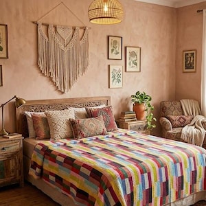 May include: A bedroom featuring a multi-coloured patchwork quilt with rectangular blocks in various hues covering a bed. The room includes a carved wooden headboard, a woven pendant light, a macrame wall hanging, and a patterned area rug.