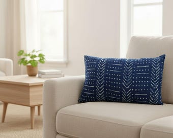 May include: A rectangular throw pillow in deep navy blue featuring a white hand-drawn pattern of vertical chevron stripes and horizontal dotted lines. The fabric has a visible woven texture, and the pillow is positioned on a light beige sofa.