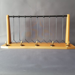 Puede incluir: Un perchero de pared de madera con una rejilla de metal negro y cinco ganchos de latón.
