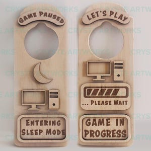 May include: Two wooden door hangers with a gamer theme. The left hanger says "Game Paused" and has a crescent moon and a computer monitor icon. The right hanger says "Let's Play" and has a progress bar with the text "... Please Wait" and the text "Game in Progress".