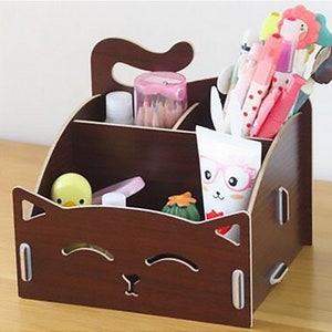 Pode incluir: Um organizador de mesa de madeira marrom em forma de gato com um rosto sorridente. O organizador tem quatro compartimentos e é perfeito para guardar canetas, lápis e outros materiais de escritório.