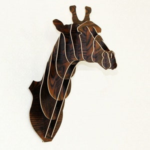 May include: A wooden giraffe head sculpture with a layered design. The sculpture is made of dark wood with a natural grain pattern. It is a wall-mounted decoration.
