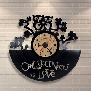 May include: Black vinyl record clock with a wood-toned clock face and black metal owl silhouettes on branches. The clock face has black numbers and hands. The vinyl record has the text "OWL you Need is Love" printed on it.
