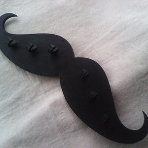 May include: Black moustache-shaped key holder with five key hooks.