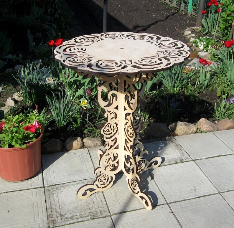 Pu&ograve; includere: Un tavolo in legno con un piano rotondo e intricati disegni di rose intagliati nella superficie e nelle gambe. Il tavolo &egrave; di colore marrone chiaro e ha un aspetto rustico e vintage.