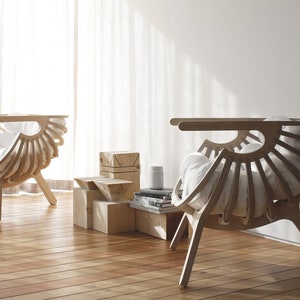 Puede incluir: Dos sillas de madera con cojines blancos, diseñadas en forma de abanico, se colocan en una habitación con suelo de madera y una pared blanca. Las sillas están hechas de madera clara y tienen un diseño simple y moderno.