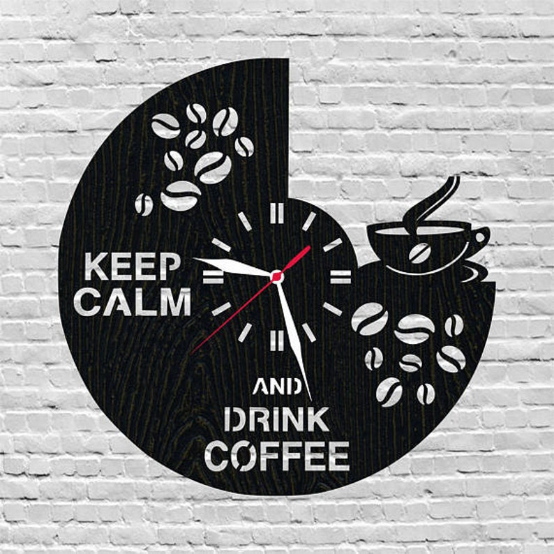 Puede incluir: Reloj en blanco y negro con un dise&ntilde;o de taza de caf&eacute; y granos de caf&eacute;. La esfera del reloj dice "Keep Calm and Drink Coffee".