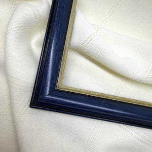 May include: A rectangular picture frame featuring a dark navy blue outer border with a visible wood grain texture and a thin, metallic silver inner trim that creates a sharp contrast against the deep blue finish of the frame's outer edge.