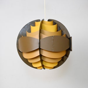 May include: A brown and yellow geometric pendant light fixture with a spherical shape. The light fixture is made of multiple overlapping panels that create a unique and modern design.