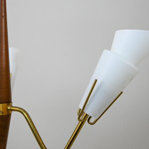 Może przedstawiać: Lampa wisząca w stylu mid-century modern z drewna i mosiądzu z białymi kloszami szklanymi. Lampa wisząca ma zakrzywione ramię i jedną żar&oacute;wkę.