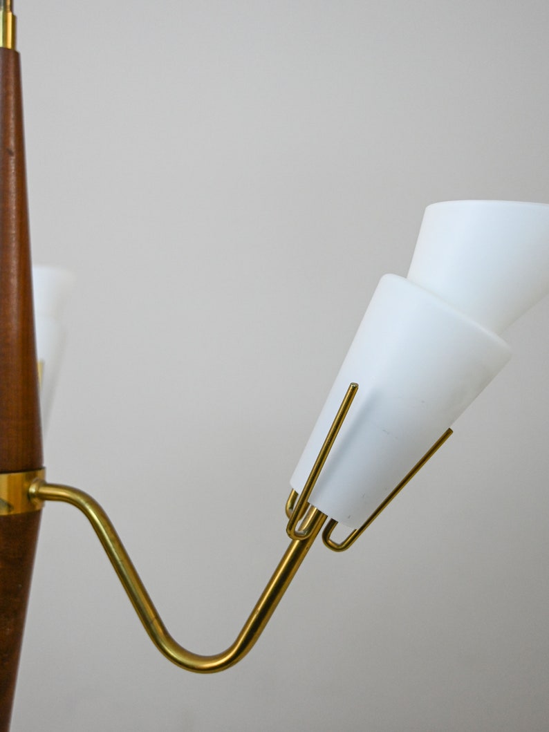 Może przedstawiać: Lampa wisząca w stylu mid-century modern z drewna i mosiądzu z białymi kloszami szklanymi. Lampa wisząca ma zakrzywione ramię i jedną żar&oacute;wkę.