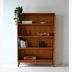 Librería vintage escandinava de roble con cuatro estantes y patas moldeadas, diseño minimalista de los años 50 y 60.