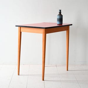 May include: A red and black table with a wooden frame and four legs. The table is about 30 inches tall and 24 inches wide.