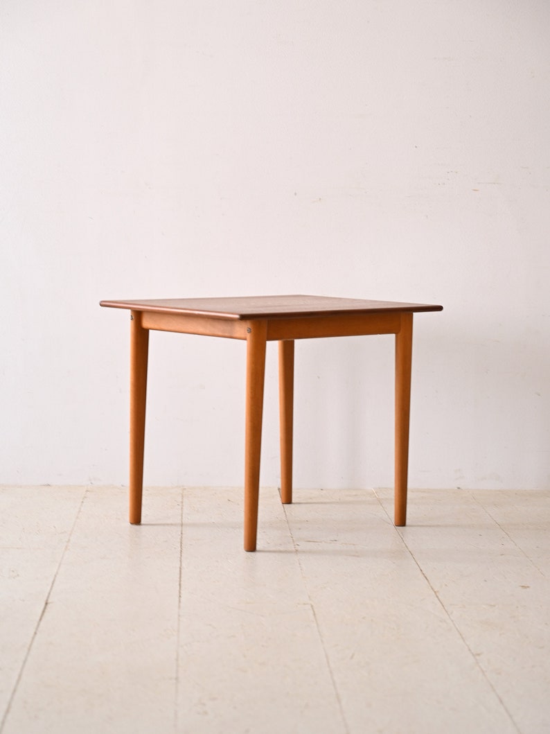 May include: A square wooden table with four legs. The table is made of light brown wood and has a simple design.