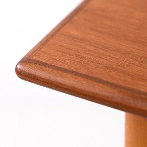 May include: Close-up of the corner of a wooden table top. The table top is a rich brown colour with a slightly darker border.