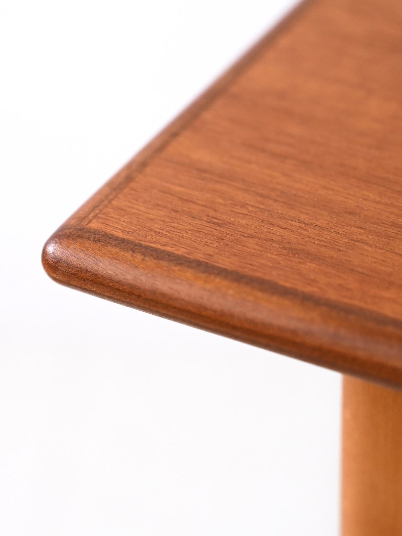 May include: Close-up of the corner of a wooden table top. The table top is a rich brown colour with a slightly darker border.