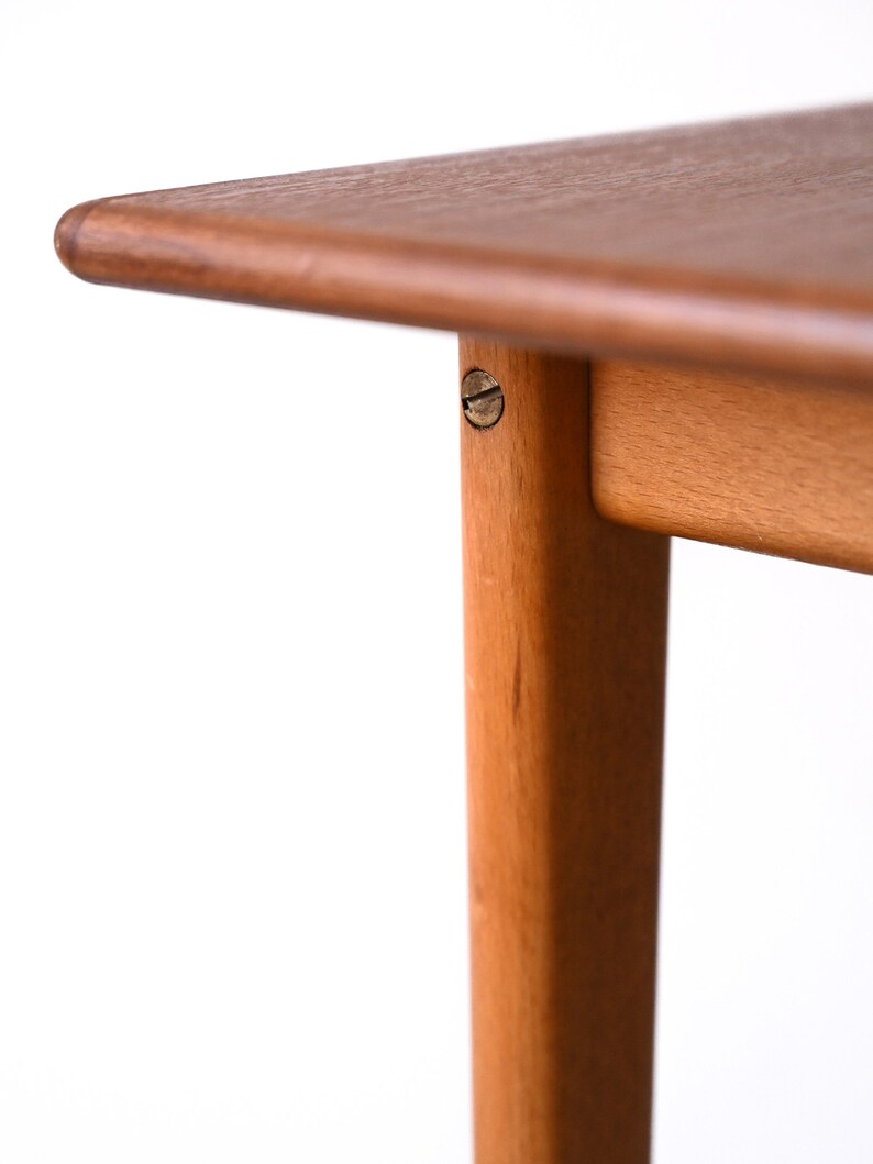 May include: Close-up of a wooden table top with a rounded edge and a visible screw in the leg.