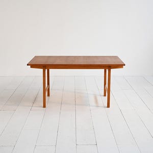 Puede incluir: Una mesa rectangular de madera con acabado marrón claro. La mesa tiene cuatro patas rectas y un diseño sencillo. La mesa mide aproximadamente 122 cm de largo, 61 cm de ancho y 71 cm de alto.