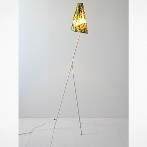 Può includere: Una lampada da terra a treppiede bianca con un paralume a motivi verdi e gialli.