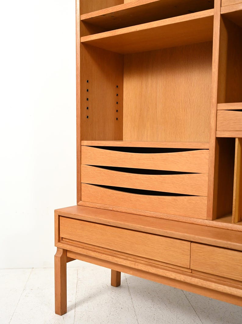 May include: A light brown wooden cabinet with multiple shelves, drawers, and a lower cabinet. The cabinet has a mid-century modern design with clean lines and a natural wood finish. The drawers have curved, black-lined accents.