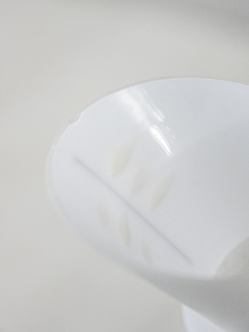 Może przedstawiać: Biały plastikowy pojemnik z małym, płytkim, zaokrąglonym przekrojem. Pojemnik ma cienką, wypukłą linię wzdłuż dna przekroju.