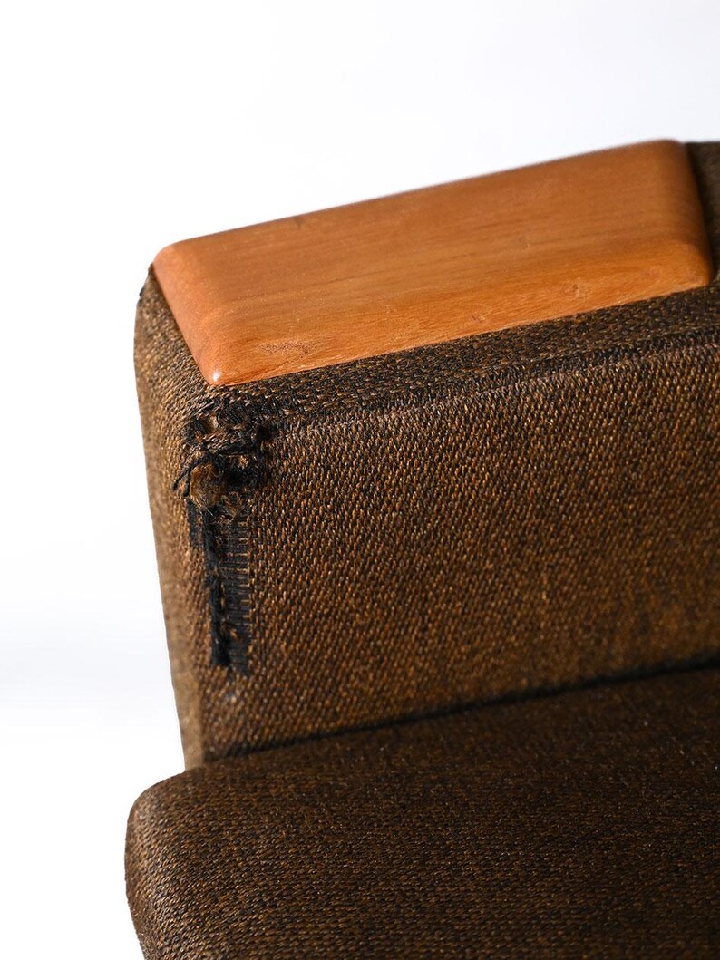 Pu&ograve; includere: Primo piano di una sedia in tessuto marrone con una parte superiore in legno. La sedia ha una tappezzeria in tessuto marrone con una texture sottile. La parte superiore della sedia &egrave; in legno marrone chiaro.