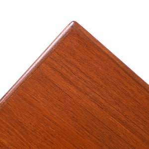 May include: Close-up of a corner of a wooden table top. The wood is a rich reddish-brown colour with a smooth, polished finish.