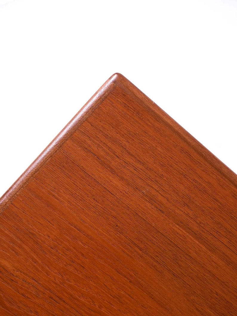 May include: Close-up of a corner of a wooden table top. The wood is a rich reddish-brown colour with a smooth, polished finish.