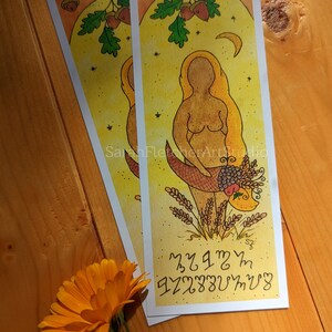 May include: A yellow and brown illustration of a woman standing in a field of wheat. She is holding a basket of fruit and flowers. The background is a yellow sky with a crescent moon and stars. The text "Malam" and "Szczepan" is written in black at the bottom of the image.