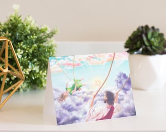 May include: A greeting card with a painting of a man and a woman on a swing in the clouds. The man is wearing a red robe and the woman is wearing a green dress. The sky is blue with white clouds and the sun is shining.