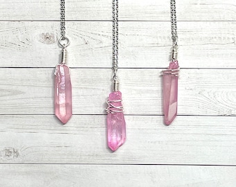 May include: Three silver necklaces with pink crystal pendants. Each pendant is wrapped in silver wire.