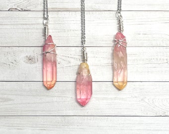 May include: Three silver chain necklaces with pink and yellow crystal point pendants wrapped in silver wire.