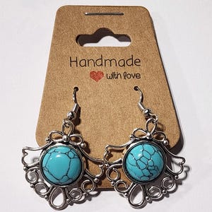 May include: Turquoise blue stone earrings with a silver filigree design. The earrings are handmade and have a heart with the words "with love" on the card.