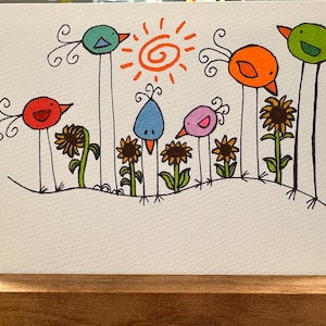 May include: A whimsical illustration featuring colorful birds with long legs, each perched above sunflowers. The birds are in shades of red, blue, orange, green, and pink. A bright orange sun with spiral details shines above the birds.