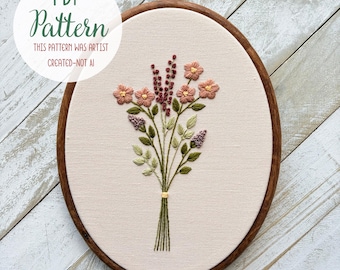 May include: An oval embroidery hoop with a floral design. The embroidery features a bouquet of pink and purple flowers with green leaves, tied with a yellow thread. The text "PDF Pattern" and "THIS PATTERN WAS ARTIST CREATED-NOT AI" are in a white circle.
