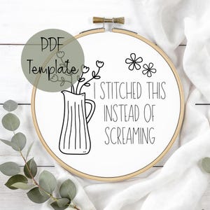 May include: A white embroidery hoop with the text "I STITCHED THIS INSTEAD OF SCREAMING" in black. The design includes a vase with flowers and two simple flower illustrations. A PDF template is indicated in a green circle.