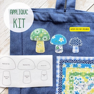 May include: A denim tote bag with three mushroom applique patches in various floral patterns. The image includes a kit with fabric pieces and mushroom pattern templates. Text on the image reads "APPLIQUE KIT" and "DENIM TOTE NOT INCLUDED".