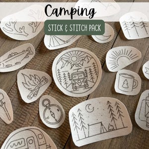 May include: A collection of white adhesive embroidery patterns featuring camping themes, including a camper van, mountains, trees, a campfire, a compass, a mug, and a tent. The text Camping STICK & STITCH PACK is printed in black and white.
