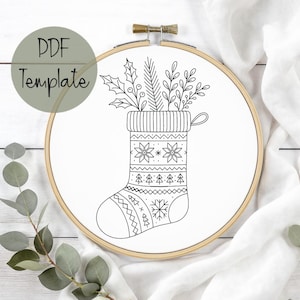 May include: A black and white embroidery hoop featuring a Christmas stocking design. The stocking is filled with greenery and decorated with snowflakes and trees. The text "PDF Template" is in a green circle.