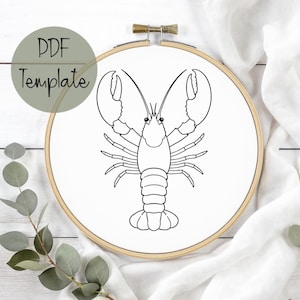 May include: A black and white line drawing of a lobster is centered on white fabric stretched within a wooden embroidery hoop. The text "PDF Template" is in a green circle in the upper left.
