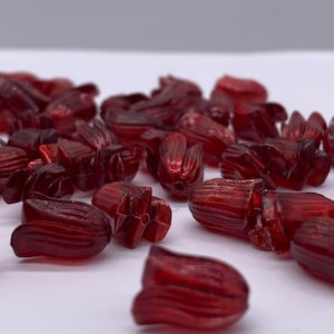 May include: A group of red plastic flower-shaped beads. The beads are glossy and have a slightly translucent appearance.