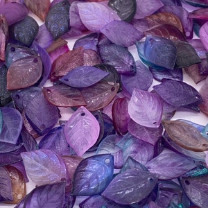 May include: A collection of iridescent purple, blue, and pink leaf-shaped charms with a hole at the top for stringing. The charms are made of resin and have a glittery finish.